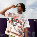 Person wearing a vintage football jersey with a graphic design, standing outdoors against a graffiti-covered wall.