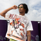 Person wearing a vintage football jersey with a graphic design, standing outdoors against a graffiti-covered wall.