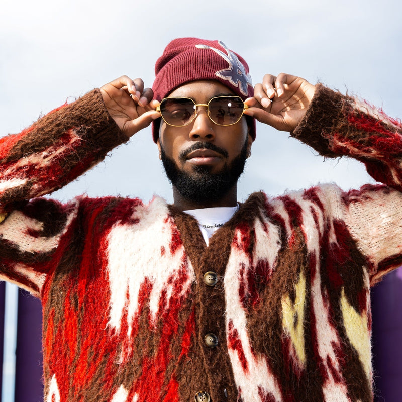 Person wearing a colorful sweater with abstract patterns in red, white, and brown.
