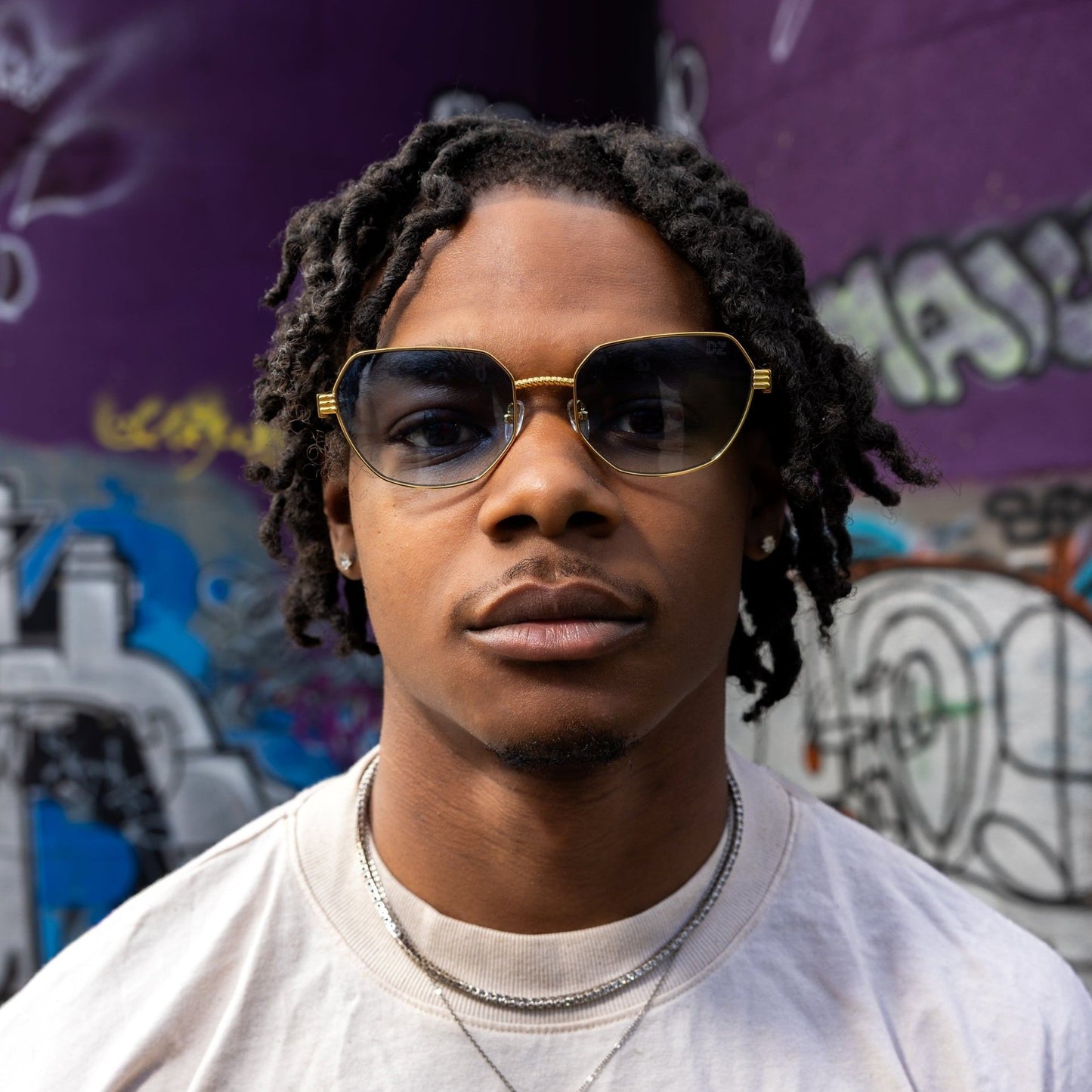 Person wearing sunglasses and a shirt with text in an urban setting