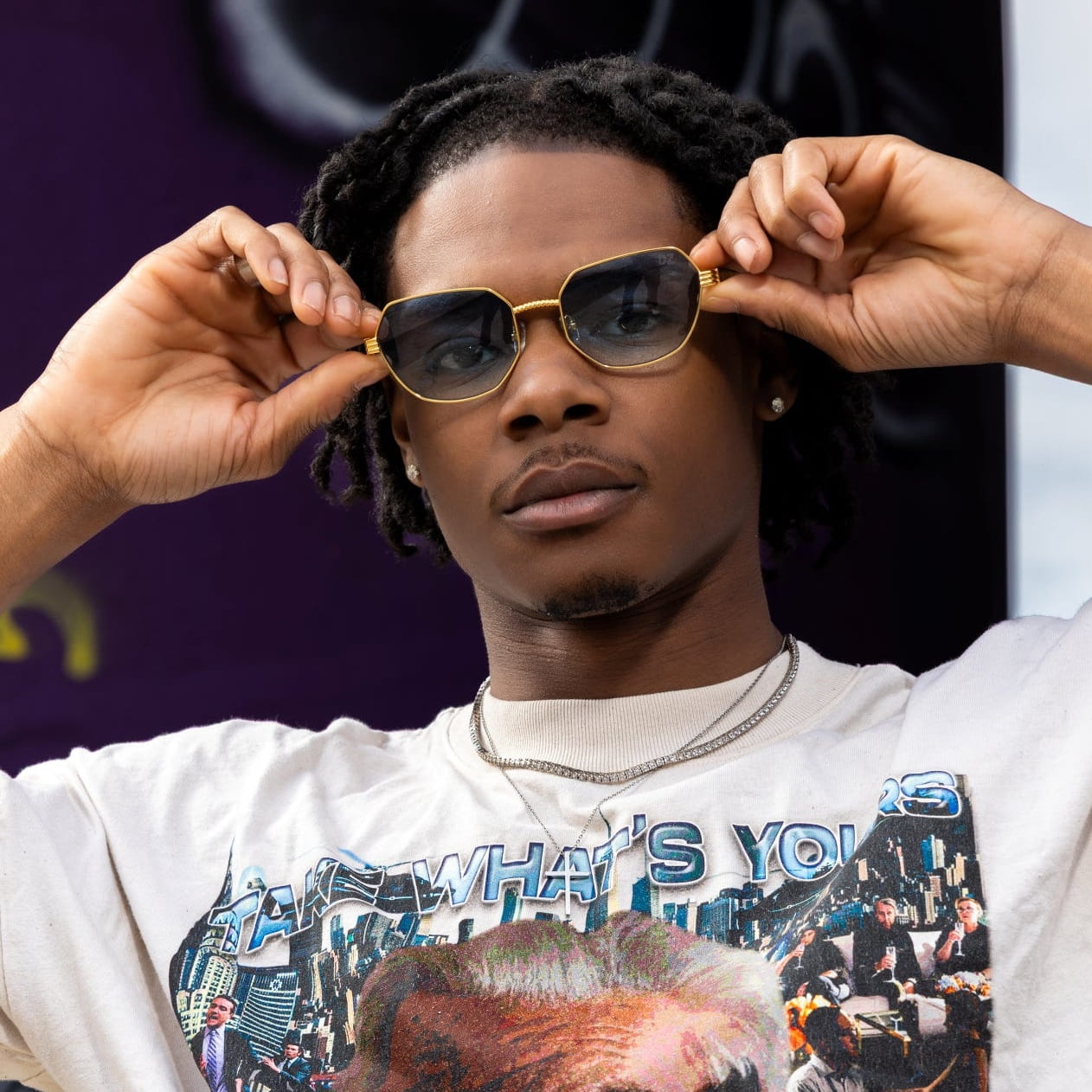 Person wearing sunglasses with a graphic t-shirt in the background