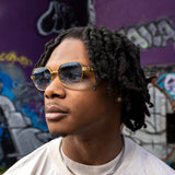 Person wearing sunglasses with a graffiti-covered wall in the background