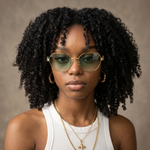 ACE Emerald hexagonal aviator sunglasses with gold frame and green gradient lenses, worn by a woman with natural hair.