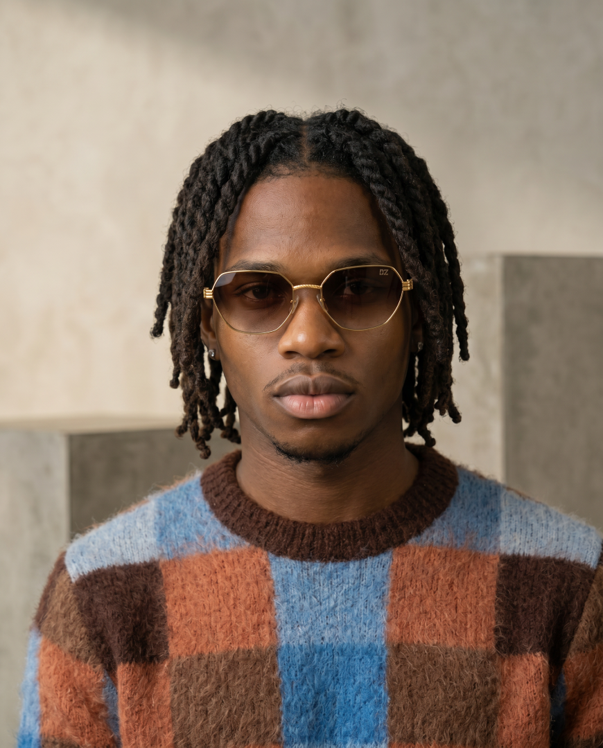 Man wearing sunglasses and a checkered sweater against a neutral background